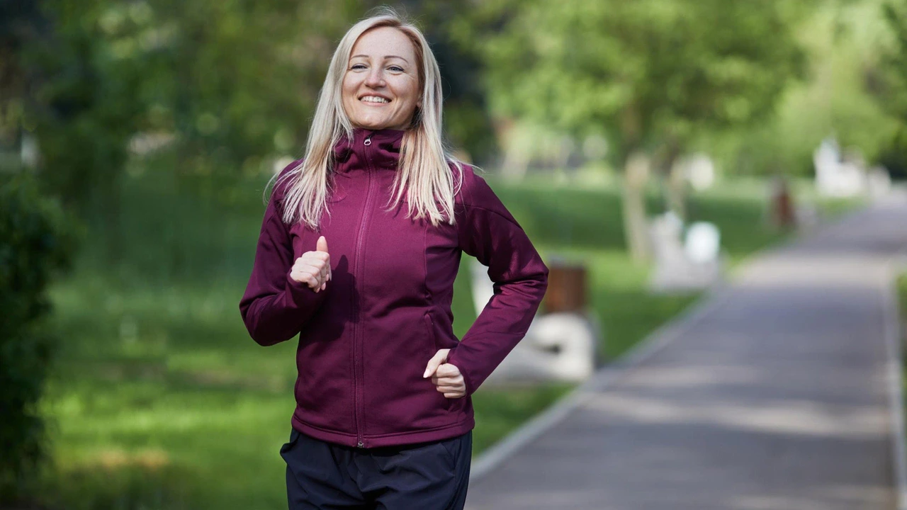 Donna sorridente cammina a passo sostenuto in un parco verde