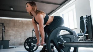 Donna over 40 esegue lo stacco da terra con bilanciere in palestra essenziale